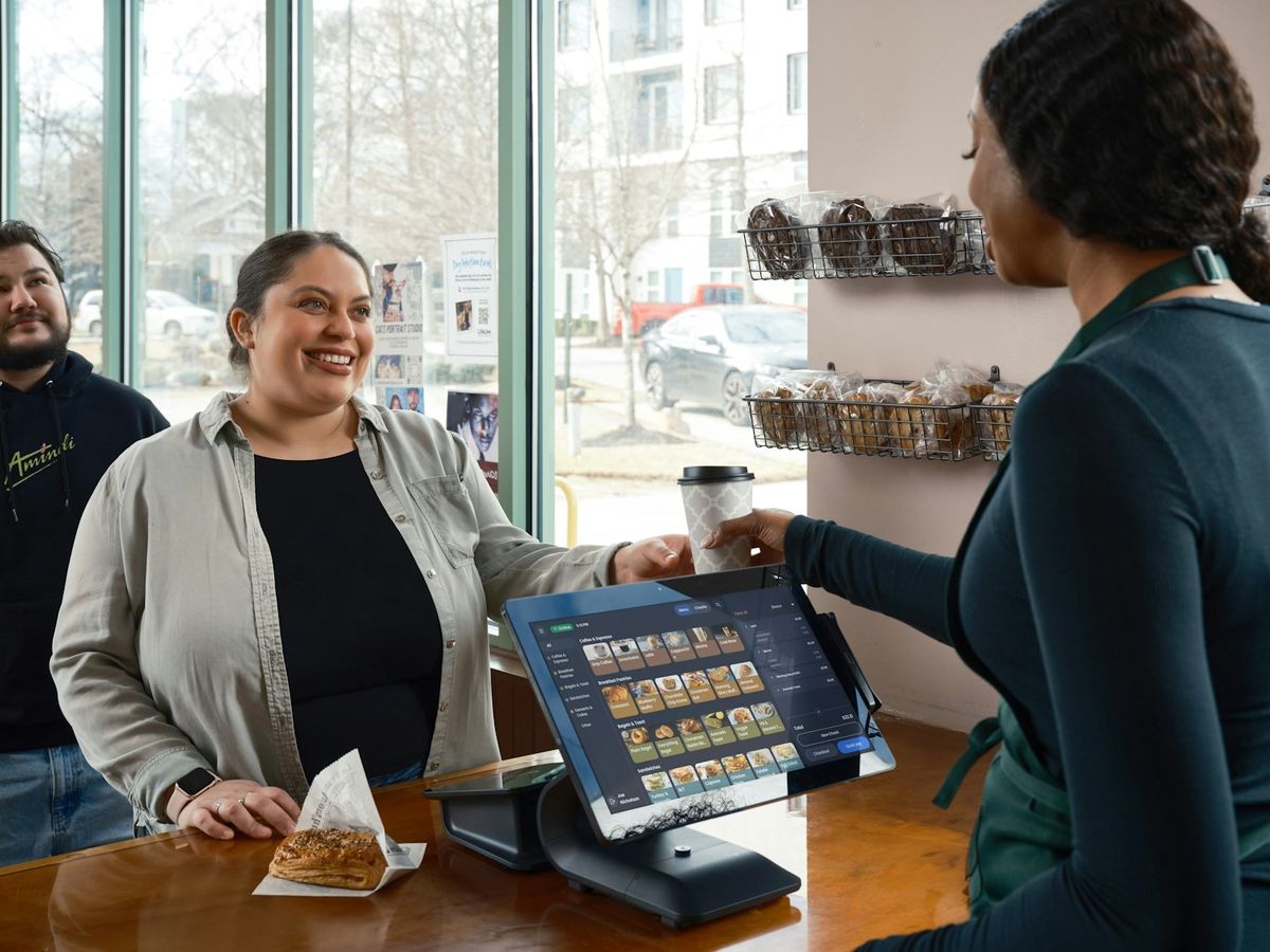 Barista atendiendo a una clienta sonriente en la caja